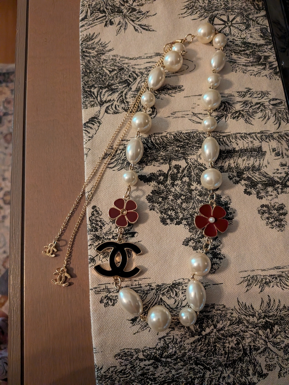 Classic Pearl Necklace with Red Flower Accents and Black Logo Charm
